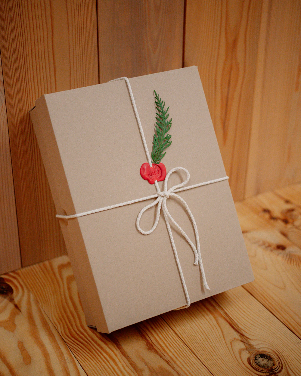 A kraft-paper gift box tied with cotton string, a red wax seal and a sprig of fir